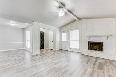 Unfurnished living room with ceiling fan, a fireplace, lofted ceiling with beams, and light hardwood / wood-style flooring