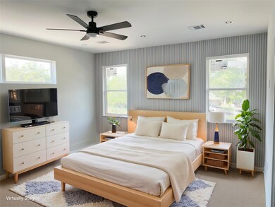 Bedroom featuring wallpapered walls, baseboards, light colored carpet, and a ceiling fan