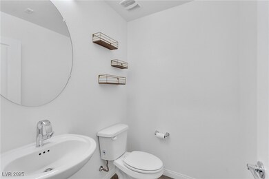 Bathroom featuring toilet, a sink, visible vents,