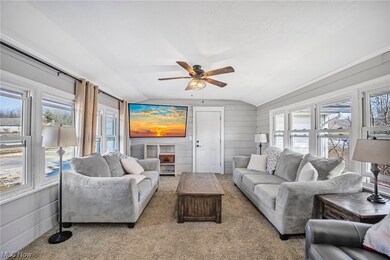 Living room featuring plenty of natural light, vaulted ceiling, ceiling fan, and light carpet