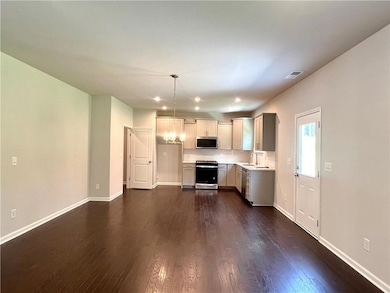 Kitchen featuring appliances with stainless steel finishes, light countertops, dark wood-style floors, recessed lighting, and hanging light fixtures