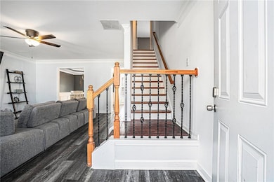 Staircase featuring ceiling fan, wood finished floors, and ornamental molding