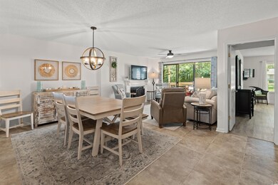 Dining area with a fireplace, a chandelier, a textured ceiling, and a ceiling fan