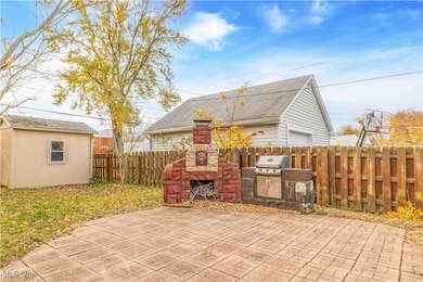 Fenced backyard featuring an outdoor stone fireplace, area for grilling, an outdoor structure, and a patio
