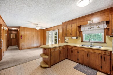Kitchen with wood cabinets, island, yellow countertops, and wood paneling walls. - 5292 Java Rd, Java, VA 24565