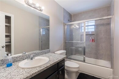 Bathroom with combined bath / shower with glass door, toilet, and vanity