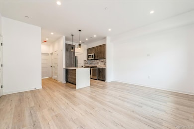 Kitchen with pendant lighting, open floor plan, light wood finished floors, dark brown cabinets, and recessed lighting.The pictures represent the model unit.