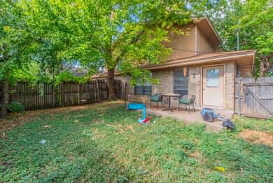Rear view of unit 521 with a gate, a patio, and brick siding