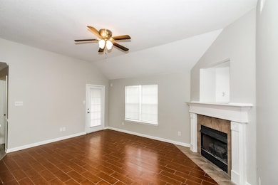 Unfurnished living room featuring vaulted ceiling, ceiling fan, a tile fireplace, and wood finished floors
