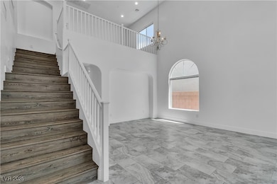 Stairway featuring arched walkways, healthy amount of natural light, a high ceiling, and a chandelier