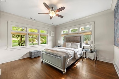 Bedroom with ornamental molding, dark wood-type flooring, and a ceiling fan