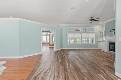 Unfurnished living room featuring plenty of natural light, hardwood / wood-style floors, and ceiling fan with notable chandelier