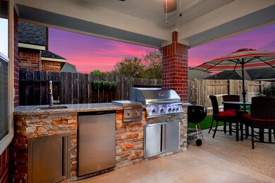Let's delve deeper into this outdoor kitchen, which features a stainless steel cooktop, grill, refrigerator space, and a kitchen sink. Take note of the granite countertops and the mosaic stone tile that beautifully complements the pool area.