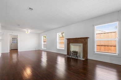 Unfurnished living room featuring dark wood-type flooring, a ceiling fan, and a tiled fireplace
