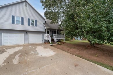 Split level home with driveway, covered porch, an attached garage, and roof with shingles