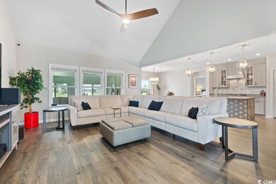 Living area with dark wood-style flooring, a ceiling fan, and high vaulted ceiling
