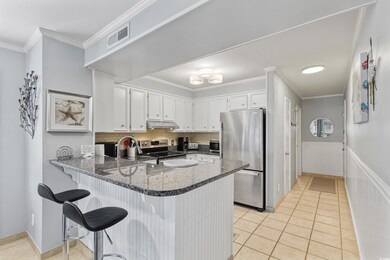 Kitchen featuring appliances with stainless steel finishes, under cabinet range hood, a peninsula, light tile patterned floors, and ornamental molding