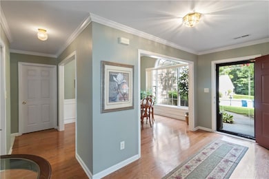 Entryway with crown molding and wood finished floors