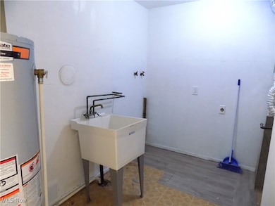 Laundry area with gas water heater, washer hookup, and light wood finished floors