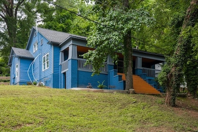 View of front of property featuring a front yard, a shingled roof, stairway, and covered porch