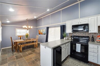 Kitchen with a peninsula, white cabinetry, black a