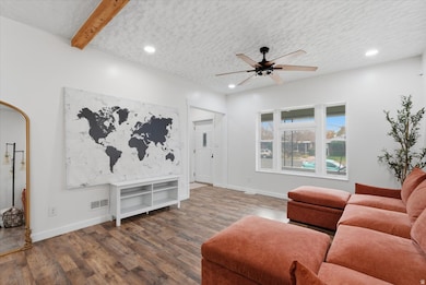 Living room with a textured ceiling, recessed lighting, wood finished floors, a ceiling fan, and beam ceiling