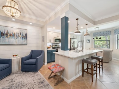 Kitchen featuring decorative light fixtures, a kitchen breakfast bar, white cabinets, crown molding, and appliances with stainless steel finishes