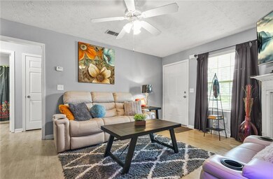 Living area with a textured ceiling, light wood finished floors, and a ceiling fan