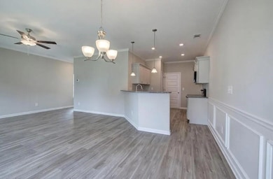 Kitchen with ornamental molding, open floor plan, dark countertops, a sink, and ceiling fan
