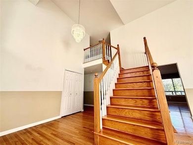 Staircase featuring wood finished floors, a chandelier, and high vaulted ceiling