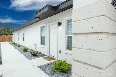 View of exterior entry with stucco siding and fence