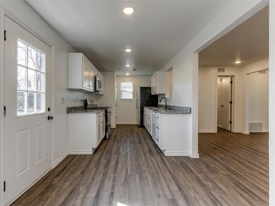 Kitchen featuring appliances with stainless steel finishes, dark wood-style flooring, baseboards, white cabinetry, and recessed lighting