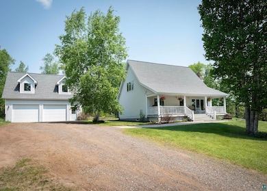 Cape cod house with driveway, a porch, a front lawn, and a shingled roof