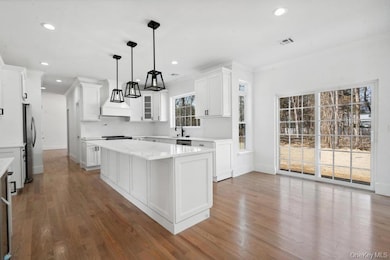 Kitchen featuring dark wood-style floors, light countertops, a kitchen island, and white cabinets