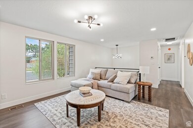 Living area with a chandelier, wood finished floors, and recessed lighting