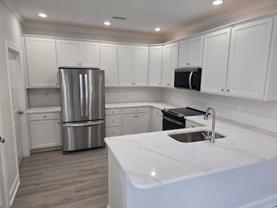 Kitchen featuring visible vents, black electric range oven, a sink, freestanding refrigerator, and a peninsula