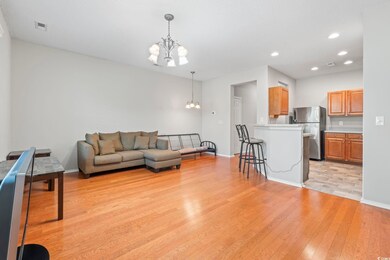 Living room with a chandelier, light wood-style floors, baseboards, and recessed lighting
