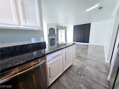 Kitchen featuring dishwasher, white cabinets, and