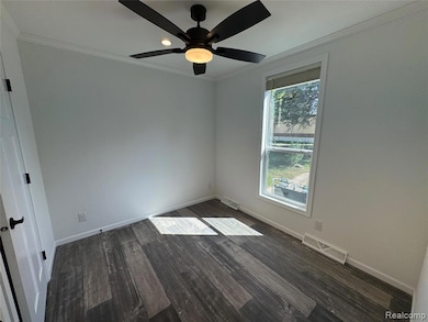 Unfurnished room with crown molding, dark wood finished floors, and ceiling fan