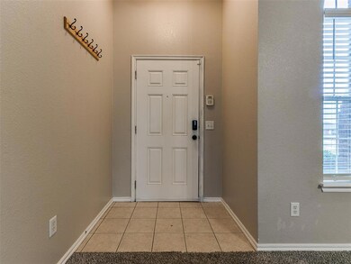 Doorway with light tile patterned floors and baseb