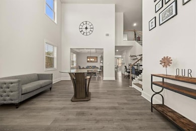 Foyer entrance with stairs, a high ceiling, plenty of natural light, dark wood-style flooring, and baseboards