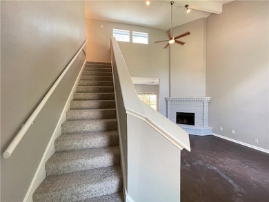 Stairs featuring a fireplace, a high ceiling, and ceiling fan