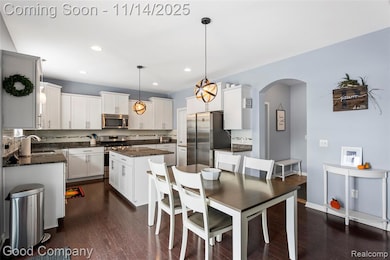 Kitchen featuring dark stone counters, dark wood finished floors, a center island, hanging light fixtures, and stainless steel appliances