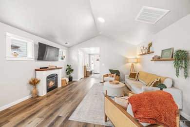 Living room with lofted ceiling, a glass covered fireplace, and wood finished floors