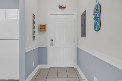 Doorway featuring tile patterned flooring, baseboa