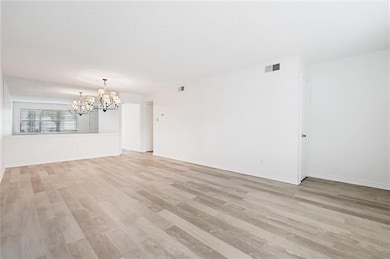 Unfurnished living room featuring a notable chandelier and light wood-type flooring