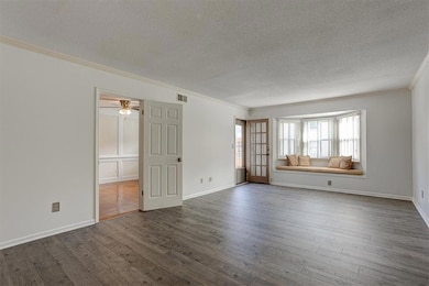 Unfurnished room with a textured ceiling, crown molding, dark wood-style floors, baseboards, and a ceiling fan