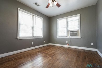 Empty room featuring dark wood-type flooring, ceiling fan, and cooling unit