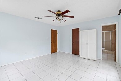 Unfurnished bedroom featuring light tile patterned floors, connected bathroom, and ceiling fan