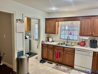Kitchen with white dishwasher, light countertops, washer / clothes dryer, and brown cabinets